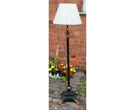 A Corinthian column standard lamp on lions paw feel, reproduction, black painted with Versailles gilt detailing. H 125 cms, w