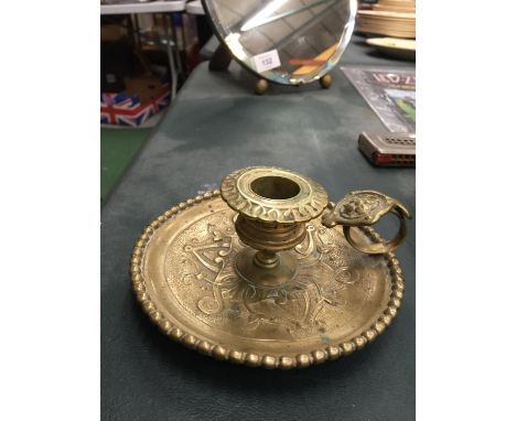 A BRASS EMBOSSED CANDLESTICK WITH HANDLE 