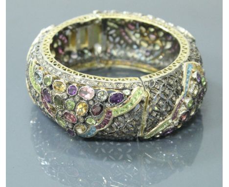 An 18 carat gold and silver mounted multi gem set bangle including diamond, ruby, sapphires, garnets, peridot, citrine, topaz