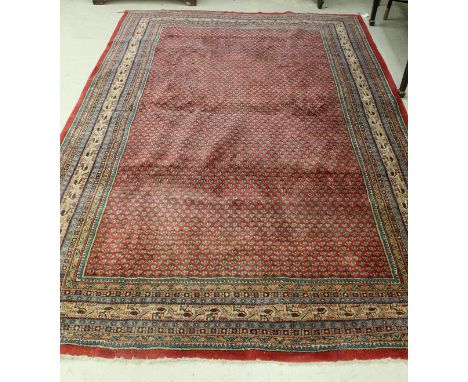 A Sarouk carpet, the central panel set with repeating hook motif decoration on a red ground within a stepped red, blue and pi