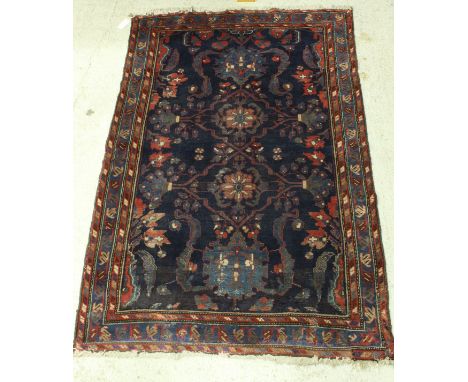 A Persian carpet, the central panel set with all-over floral design on a dark blue ground, within a stepped blue, red and cre