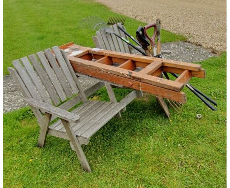 A teak garden two section bench with integral table and a collection of garden tools and a wooden stepladder