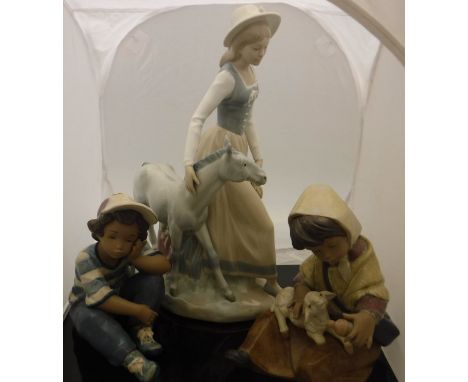 A pair of Lladro ornaments "Young Boy in Cap" and "Young Girl feeding Lamb" (2223), together with a Zaphire Lladro style figu