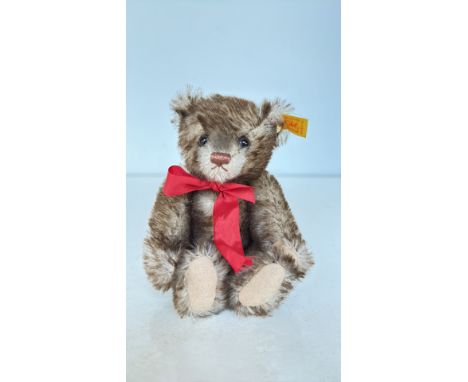 Steiff mohair teddy bear with original yellow ear tag, featuring glass eyes and a red ribbon. Made in Germany.