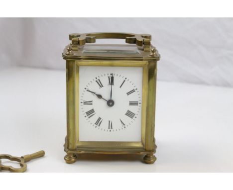Brass carriage clock raised on fur turned feet, white enamel dial with black Roman numerals and poker hands (crack running ac