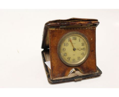 Eight day travel clock in leather case, champagne enamel dial signed E Ewen Dumfries, luminescent Arabic numerals and poker h