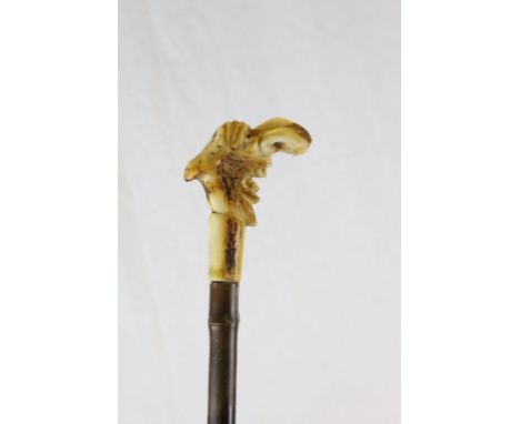 An antique walking stick with carved, grotesque bone head.