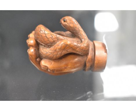 An early 20th century Japanese carved wood Netsuke of a human hand holding a Snake
