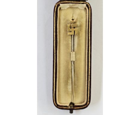 Gold-coloured stickpin&nbsp;decorated with a Buddhist symbol, registration number to reverse&nbsp;