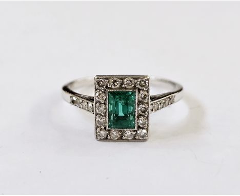 White metal, diamond and emerald ring, the central cut emerald within a border of 14 brilliant cut diamonds and with diamond 