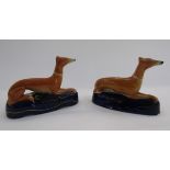 Pair of Staffordshire pottery greyhound pen rests, each ochre coloured hound seated on a dark blue