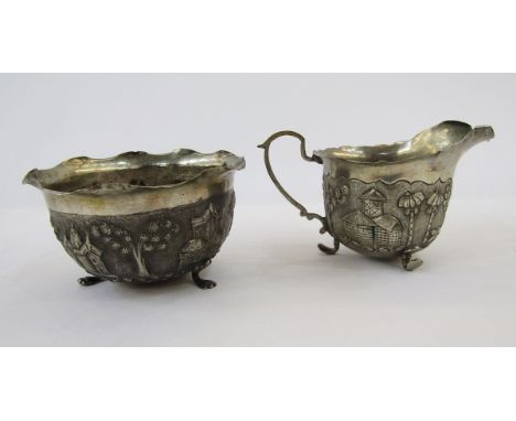 Foreign silver sugar basin and matching cream jug with scalloped inverted rim repousse decoration with buildings and exotic t