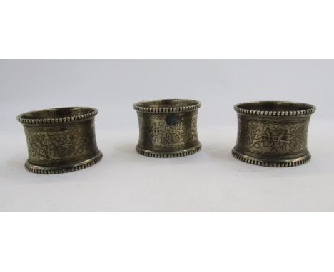 Set of three Victorian silver napkin rings, London 1875, William Evans, with gadrooned edge, foliate engraving and cartouche 