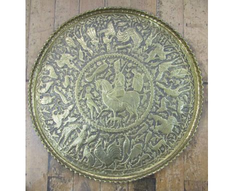 Middle Eastern, possible Qajar, embossed brass charger&nbsp;of circular form with scalloped edge, the centre with a figure on