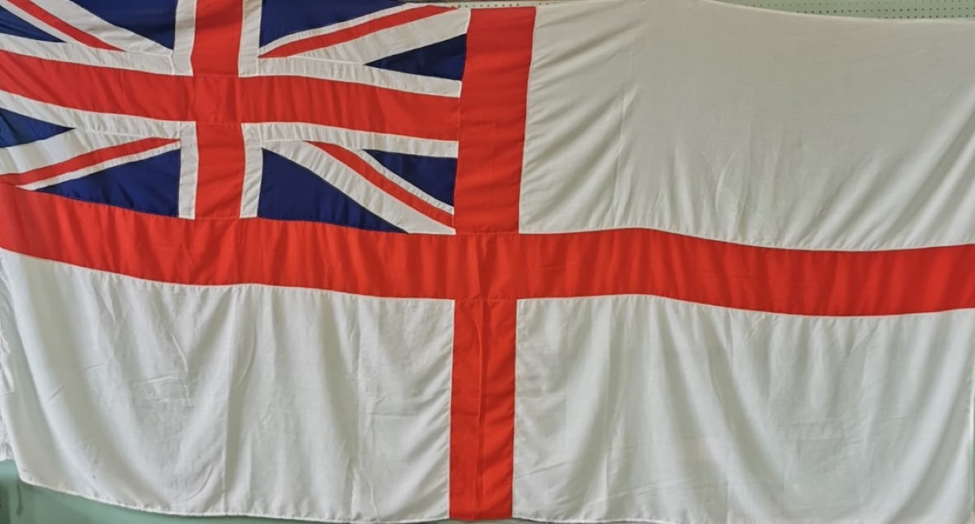 A large Royal Navy ensign flag with Union Jack to one corner.