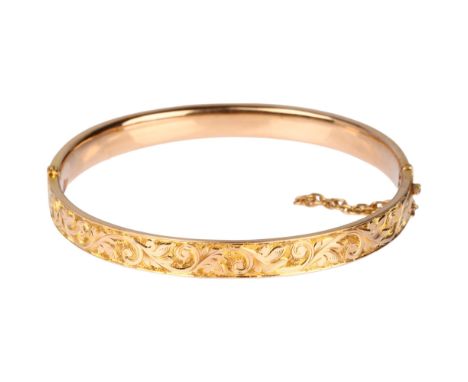 An early 20th century 15ct? rose gold hinged bangle, chased foliate decoration, band width 6.7mm, internal circumference  17c