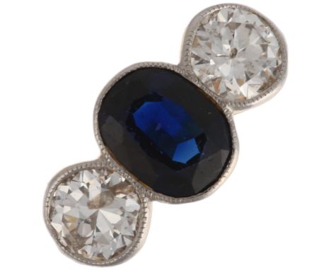 An 18ct gold three stone sapphire and diamond ring, platinum-topped, rub-over set with 0.8ct oval mixed-cut sapphire flanked 