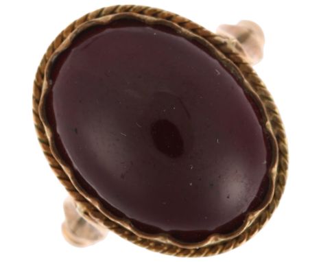 A 9ct gold foil-back garnet ring, collet set with oval cabochon garnet, within rope twist surround and closed-back reverse, s