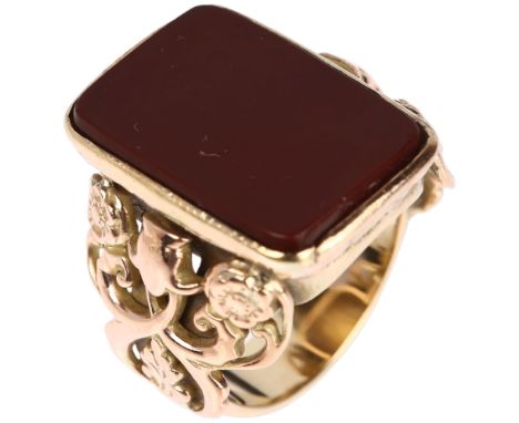 A large early 20th century 9ct gold carnelian signet ring, converted from a fob, with applied and pierce floral shoulders, ca