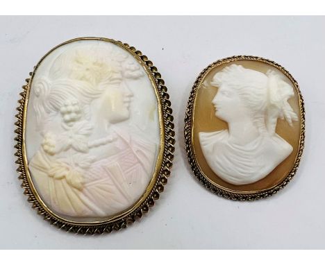 A pair of shell cameos set in 9ct gold brooch frames depicting women in classical style. Comprising a large angel skin cameo 