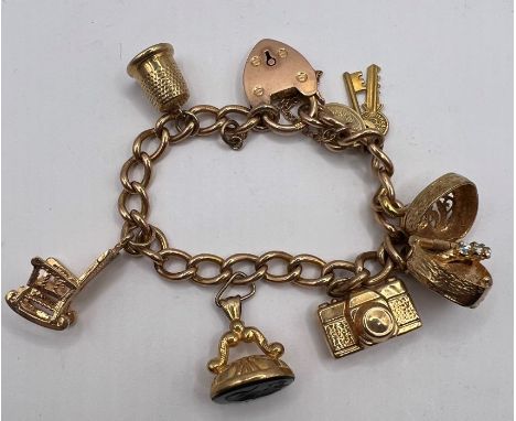 A 9ct gold charm bracelet, 16 cms long, with six charms including an articlulated box, which opens to reveal a CZ set "ring",