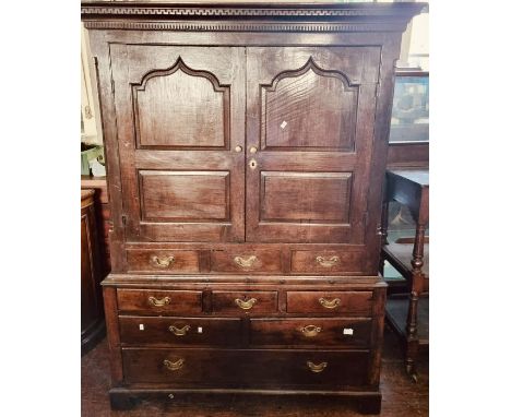 A George III oak linen press, circa 1760, dental carved moulded cornice, above a twin moulded arch cupboards over three friez