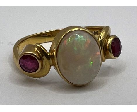 An 18 carat gold Opal and ruby set dress ring in a scroll design. Hallmarked London 1988. Size K. Gross weight approx 2.6 gra