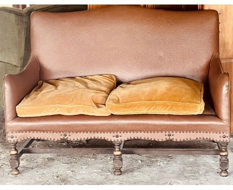 A 20th century leather and oak sofa, cartouche shaped back scrolling arms, serpentine apron mounted with brass studs, raised 