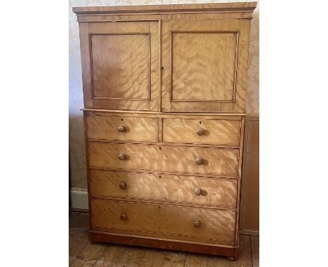 A Victorian birdseye maple linen press, circa 1850, moulded cornice, above two panel doors enclosing linen trays, the base fi