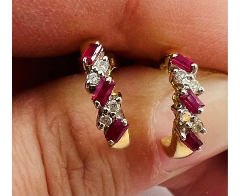 A pair of ruby and diamond 18ct gold half hoop ear studs. Each set with three baguettes of ruby and four round brilliant cut 