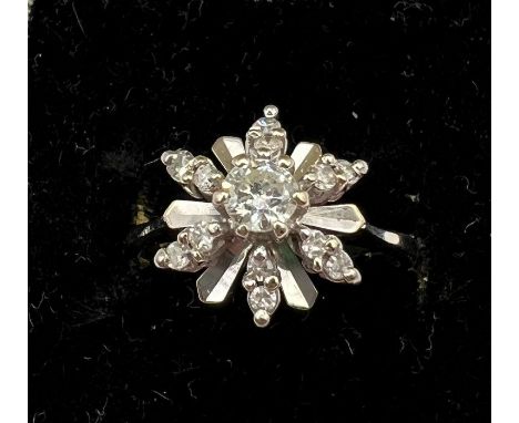 An unusual diamond cluster ring in a snowflake design in white metal. Stamped 18k. Principal diamond approx 0.25ct round bril