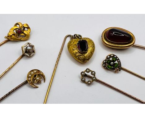 A selection of Victorian and Edwardian stick pins, all testing as 15ct gold. To include one with a suspended heart shaped cha