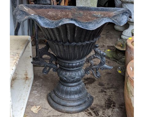 A cast iron black painted demi lune planter having a wavy border with a reeded body and scroll cast sides 77cm h x 79cm w Loc