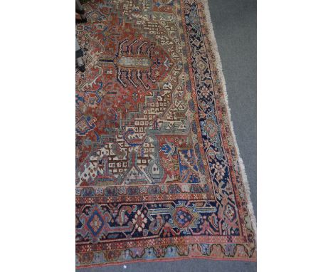 A large Iranian carpet, central cruciform medallion against a field with multiple motifs, enclosed by deep spandrels, navy br