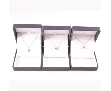 Three modern 9 carat white gold gemset pendants, a 10mm cross set with eleven sapphires, a heart shaped amethyst pendant and 