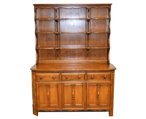 Ercol elm dresser, panel back with three shelves, base with a rectangular top, three drawers above cupboards, width 146cm, de