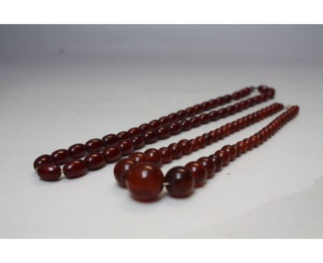 A VINTAGE SINGLE STRAND OF CHERRY AMBER BEADS, L 54 cm,  approximate W 24.3 g, together with a  vintage faux bead necklace (2