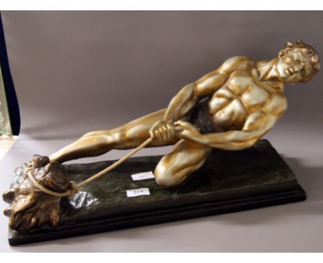 In the manner of Alexandre Ouline, a bronzed and painted ceramic figure, male removing a tree-stump. Inscribed to the natural