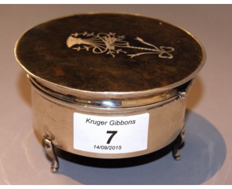 A hallmarked silver circular trinket or powder box, with an inlaid tortoiseshell panel to the hinged cover, raised on three s