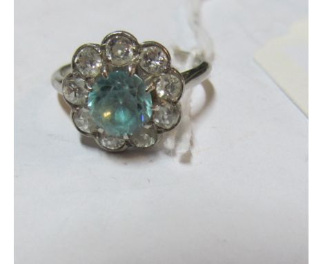 A platinum ring with nine diamonds and a light blue stone