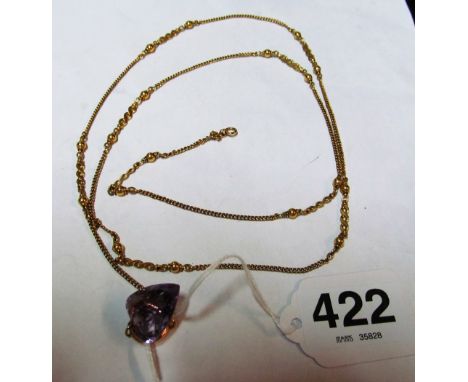 A long gold chain marked 18 with an amethyst coloured pendant