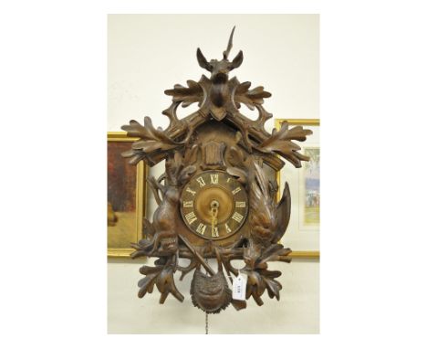 A cuckoo clock, with Roman numerals, in a carved wood case applied dead game and foliage, 55 cm high