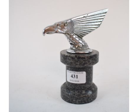 An accessory car mascot, in the form of a eagle's head with extended headdress, mounted on a plinth, 7.5 cm high