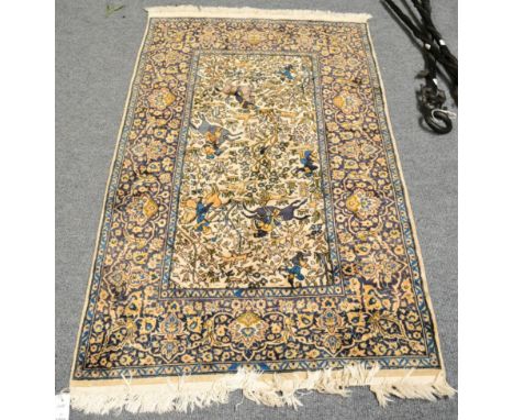 An Indian rug, depicting a hunting scene, the ivory field with huntsman in a wooded landscape enclosed by floral borders, 146