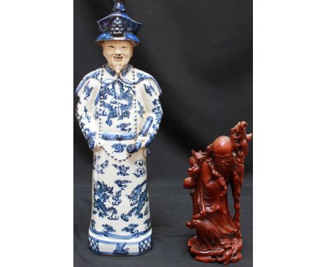 A Chinese porcelain figure of a man in Oriental robe, hat and holding a pipe, painted with blue and white decoration, glazed 