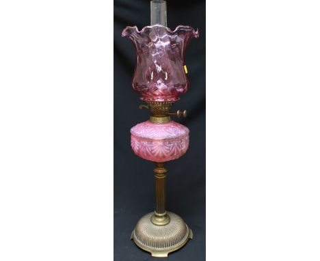 A Victorian brass and cranberry glass oil lamp, with spiral twist shade and reeded base. 64.5 cm high.