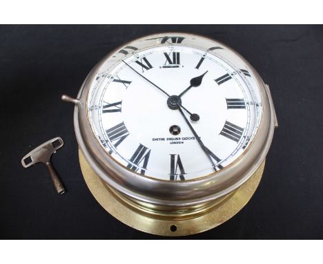 A Smiths ships brass bulk head clock, with white enamel dial and black Roman numerals, the sign inscribed Smiths English Cloc