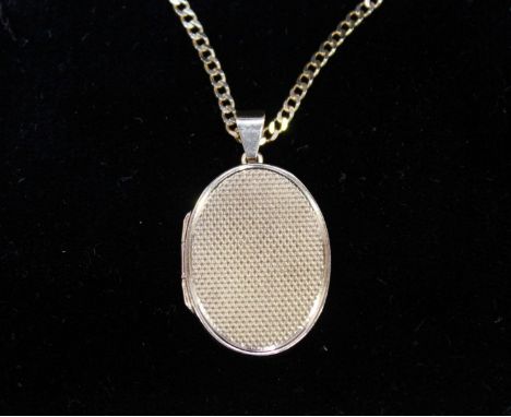 A 9ct gold oval pendant locket, with engine turned front and suspended on a 9ct gold curb link chain. 14.6 grams.