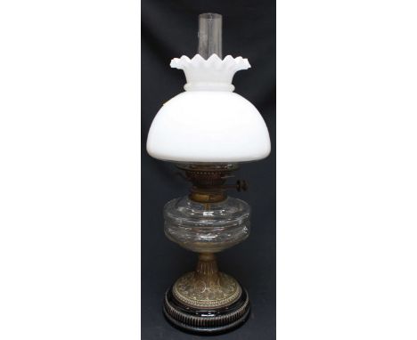 A Victorian oil lamp, with opaque glass shade, clear faceted glass reservoir, and supported on an embossed brass base. 54 cm 