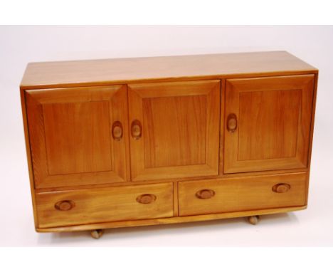 A light Ercol sideboard, fitted three cupboard doors above two drawers, 77cm high x 130cm wide x 43cm deep 